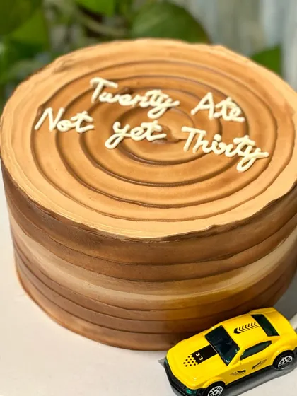 "Twenty Ate, Not yet Thirty." This witty 28th birthday cake is designed to look like a tree trunk, complete with a toy car driving on a fondant road.