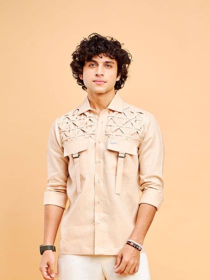 A full-length view of the cream linen shirt with unique strap details. It's the perfect balance of relaxed and stylish for a summer outing.