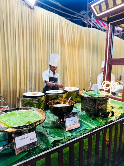 My live dosa station in action, where chefs prepare classic South Indian crepes for guests. The setup features traditional banana leaf decor and brass utensils for an authentic touch.