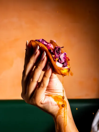 A messy, delicious-looking birria taco dripping with sauce. This shot is all about capturing the indulgent, hands-on experience of eating a great taco.