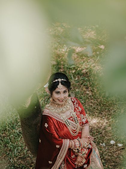 A dreamy, artistic bridal portrait. Shooting through leaves adds a natural frame and a sense of peeking into a private, serene moment.