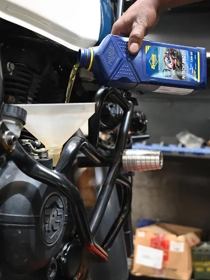 Pouring fresh Putoline oil into the Himalayan. Regular oil changes are the lifeblood of a healthy engine.