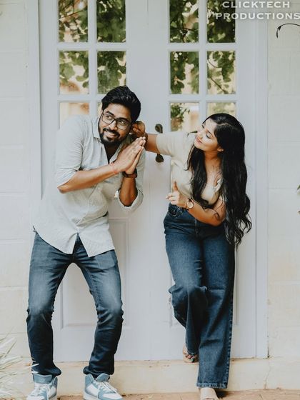 A playful and fun moment with a couple by a white door, striking a goofy pose.