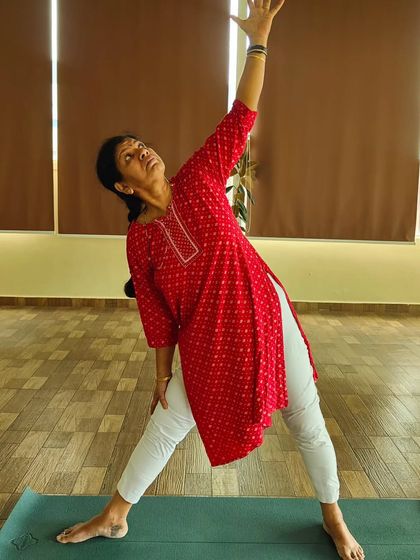 A student demonstrates Trikonasana (Triangle Pose). This foundational pose is excellent for stretching the sides of the body, hamstrings, and opening the hips, which helps in relieving back stiffness.