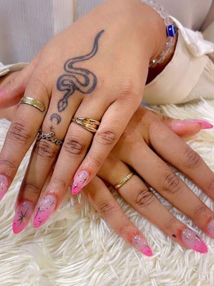 Your nails are the perfect accessory to your personal style. Here, our pink starry nail extensions beautifully complement the client's hand tattoos.