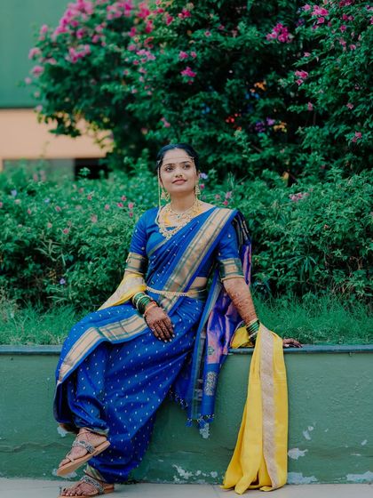 A stylish portrait of the bride posing against a green wall, her blue and yellow navari saree creating a beautiful color contrast.