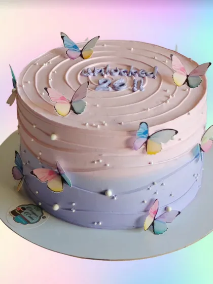 A butterfly-themed cake with a soft pink and purple ombre effect. The delicate, fluttering butterflies give the cake a light and airy feel.