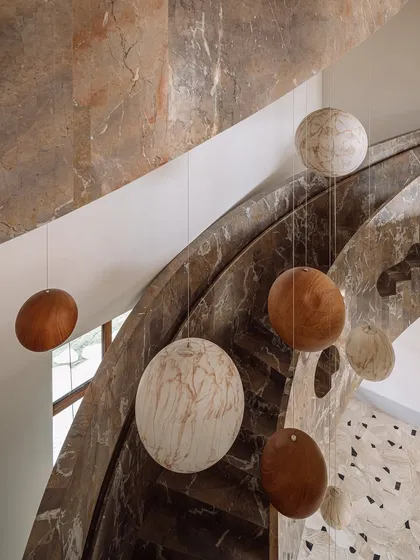 We transformed this stairwell into a surreal experience with a 'confetti carnival' installation. Oversized spheres of wood and marble are suspended by cables, and they light up in the evening to create a magical journey between floors.
