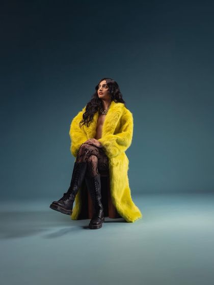A striking portrait featuring a bright yellow faux fur coat from my own fashion label. This image shows the intersection of my work in music and fashion.