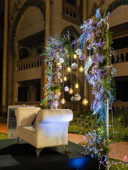 Another angle of the elegant seating area, showcasing the shimmering fabric of the sofa and the rich floral arrangements that frame it.