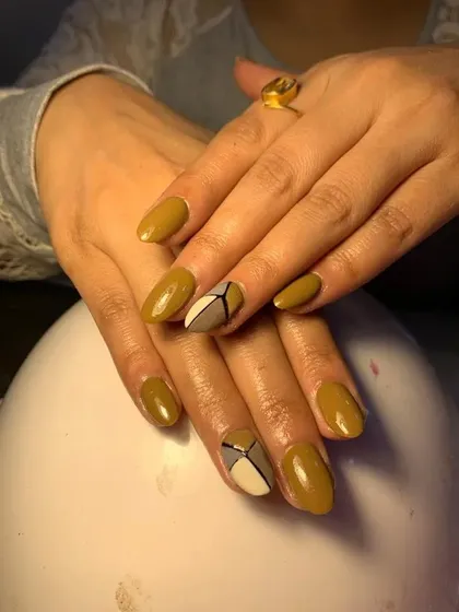 A sophisticated design with a mustard yellow base and geometric color-blocked accent nails.