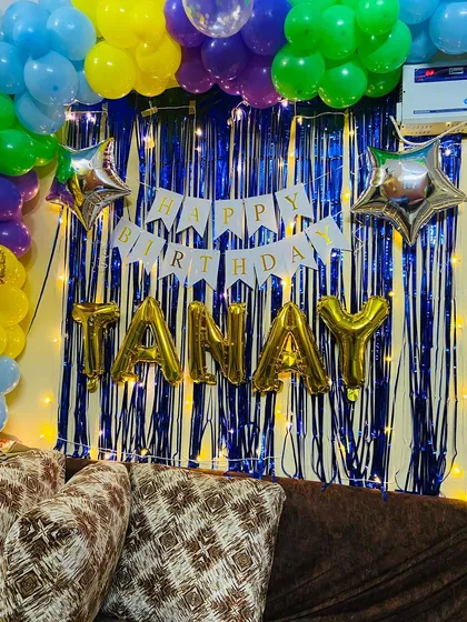 A close-up of the birthday backdrop, highlighting the 'TANAY' name balloons and the star-shaped foils that add extra sparkle.