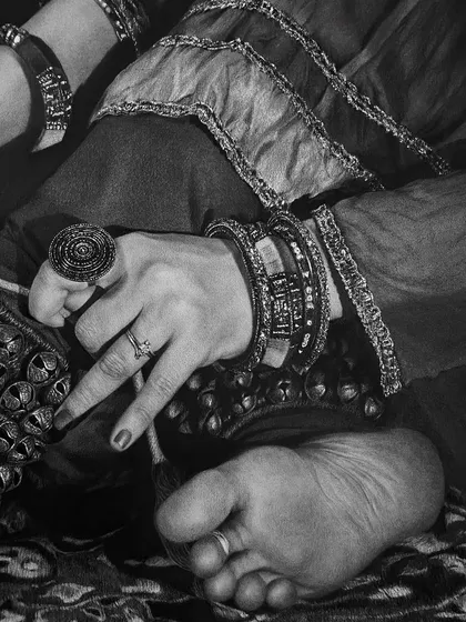 A close-up view showing the dancer's hand, adorned with rings and bangles, resting near her feet. Each element is carefully drawn to contribute to the overall narrative of cultural tradition.