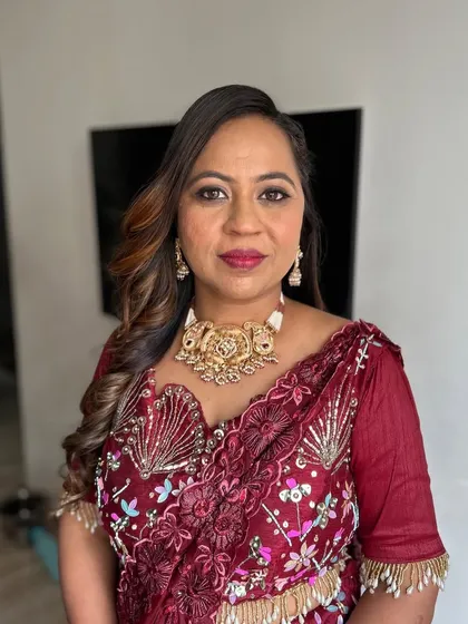 A beautiful client in a maroon embroidered saree. Her makeup is soft and warm, with a focus on her eyes.