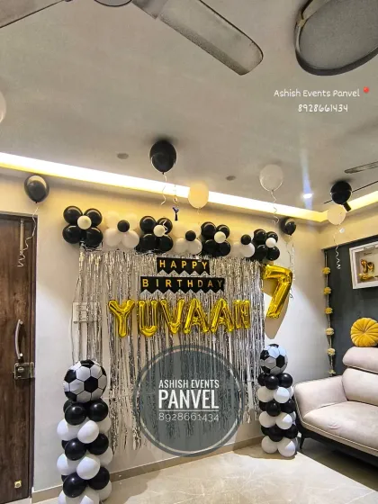 A Football theme birthday decoration for a 7th birthday. The black and white balloon pillars are designed to look like soccer balls, perfect for a sports-loving kid.