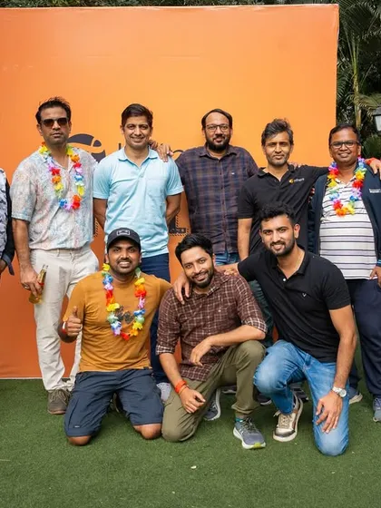 A corporate team poses for a group photo, all smiles after a day of fun and bonding at their annual event.