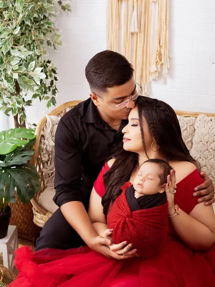 A tender moment with dad kissing mom's forehead as they both hold their new baby. This is a classic and timeless family portrait.