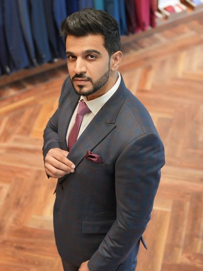 A high-angle shot of the client's grey suit, emphasizing the fit across the shoulders and chest. The choice of a rich burgundy tie and pocket square adds a touch of personality.