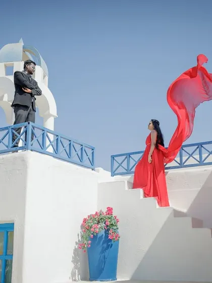 A vibrant, Santorini-themed set provides a stunning backdrop for this dramatic shot. The flowing red dress against the crisp white and blue architecture creates a high-impact, movie-poster look for your pre-wedding album.