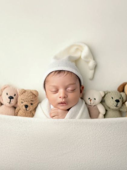 Tucked in and surrounded by friends. This sweet shot of a newborn sleeping under a blanket with a row of teddy bears is simply heartwarming.