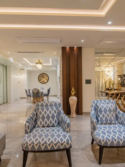 This view from the living area looks towards the dining room, showcasing the open-concept layout. A large mirror wall in the foyer reflects the space, adding depth and a sense of luxury.