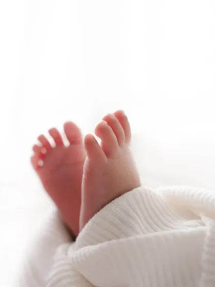 Ten tiny toes peeking out from a soft white blanket. This classic newborn shot focuses on the adorable details that change so quickly.