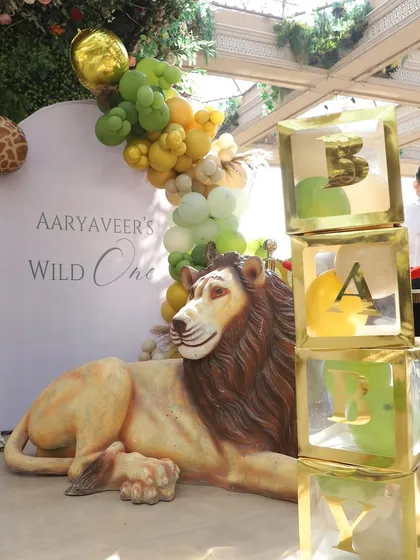 A life-size lion prop guards the "BABY" blocks, adding a regal touch to this high-end jungle party decor.