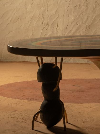 A detail shot of the Weavers Ant Table, showing the sculptural ant-like leg supporting the large terrazzo top. This highlights the blend of artistic form and structural function.