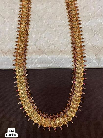 A classic kasu mala or coin necklace, made from 92.5 silver with gold plating. This flexible necklace is adorned with ruby-colored stones, giving it a timeless and traditional appeal.