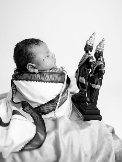 A different angle of the baby looking towards the idols, creating a narrative of devotion and peace in this monochrome photograph.