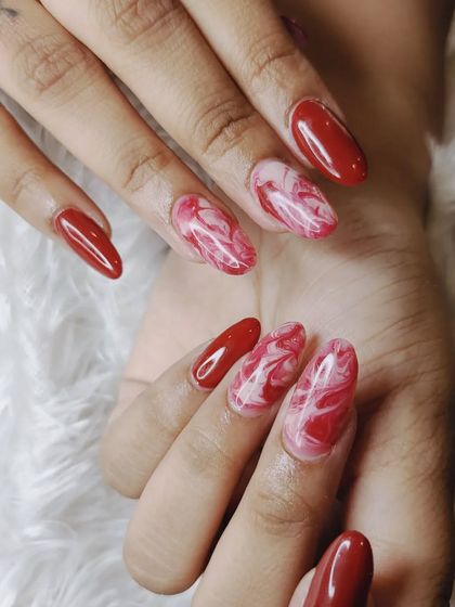 A different angle of the red and white marble design, highlighting the unique, fluid pattern on each nail.