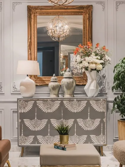 A detailed close-up of a patterned console table, showcasing the intricate design and elegant styling. This image emphasizes the importance of curated decor, like the grand mirror and fresh flowers, in creating a luxurious atmosphere.