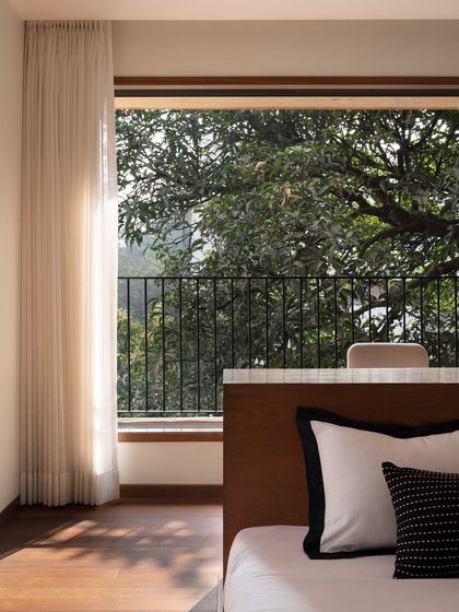 A detail of the son's bedroom, showing the custom headboard that doubles as a partition. The design cleverly incorporates the bed into the room's layout while maintaining a connection to the window and the nature outside.