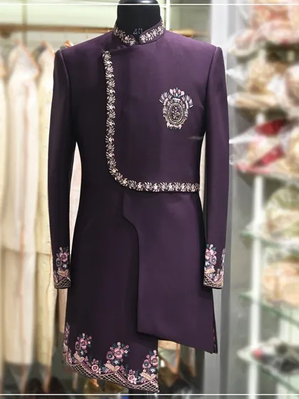 For the modern groom who wants something unique for his Sangeet or engagement. This is an asymmetrical Indo-western suit in a deep purple, featuring intricate embroidery on the cuffs, collar, and hem. It’s a perfect fusion of traditional design and contemporary tailoring.