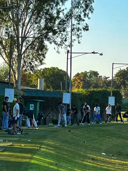 A wide shot of the range, showing groups of golfers enjoying their weekend practice session.