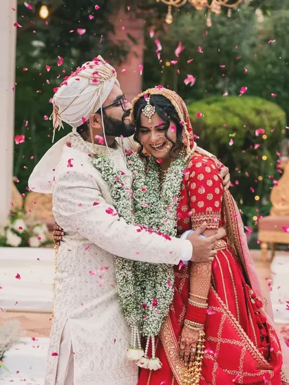 Pure, unscripted joy. A candid shot of the couple embracing under a shower of petals right after the ceremony, capturing a memory that is both beautiful and real.