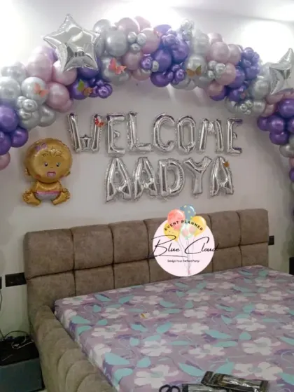 A 'Welcome Aadya' bedroom decoration with a purple and silver balloon arch over the bed.
