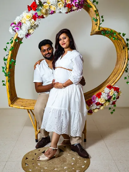 For a more modern and styled maternity shoot, I use props like this heart-shaped frame and a clean background. This shows a different style, focusing on the couple in a beautifully composed studio setting.