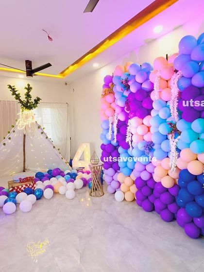 A cozy and fun home birthday decoration featuring a colorful balloon wall and a canopy tent filled with balloons, creating a playful atmosphere.
