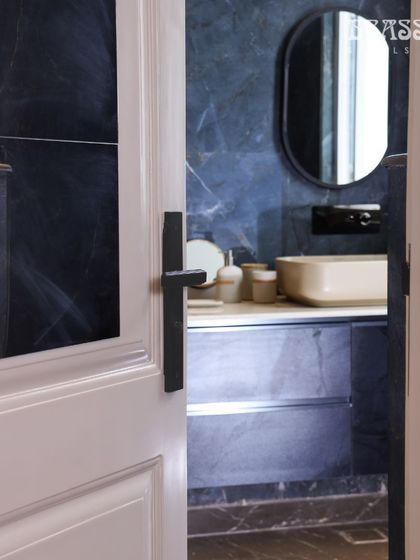 A view into the modern bathroom, where the black handle complements the dark marble and sleek fixtures.
