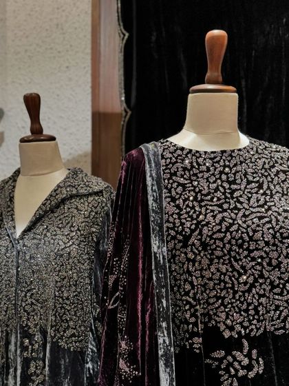 A close-up of the intricate silver embroidery covering the yoke of a charcoal grey velvet outfit.