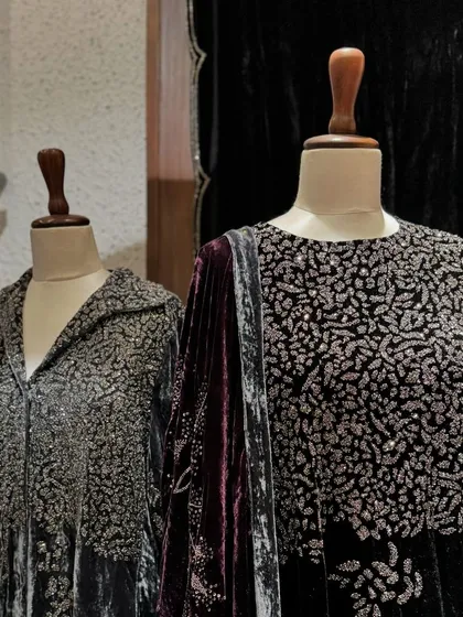 A close-up of the intricate silver embroidery covering the yoke of a charcoal grey velvet outfit.