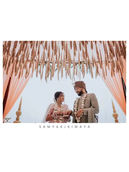 A lovely shot of a couple during their ceremony, framed by a rustic, draped mandap. Their shared look captures the significance of the moment, blending tradition with natural beauty.