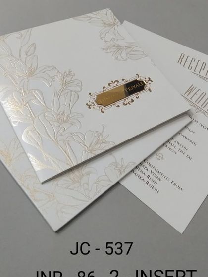 This elegant white invitation features a gold foil lily design and a simple nameplate. The layout is clean and modern, perfect for a sophisticated wedding.