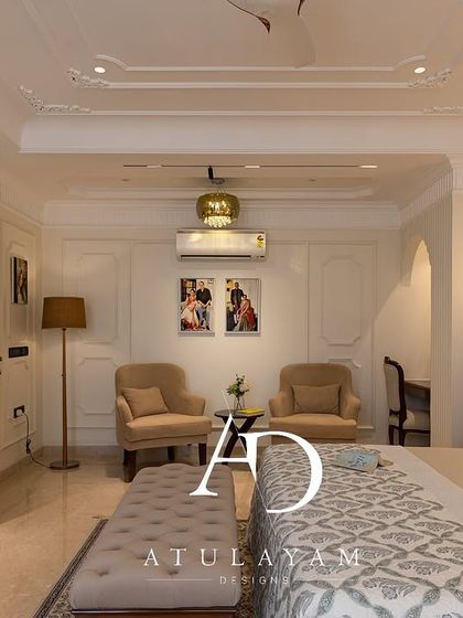 A wide view of a spacious classical bedroom, featuring ornate ceiling and wall mouldings, a seating area, and elegant furniture.
