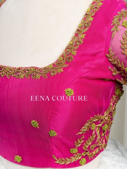 Grace in every detail. This pink net blouse features delicate leafy vines embroidered in gold and light green thread. The deep V-back and sheer sleeves add a touch of modern femininity.