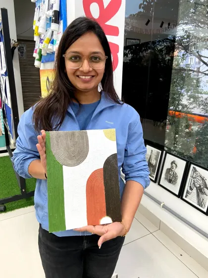 A participant holds up her finished abstract texture painting. In this workshop, you'll learn how to use different tools and pastes to create unique 3D effects.