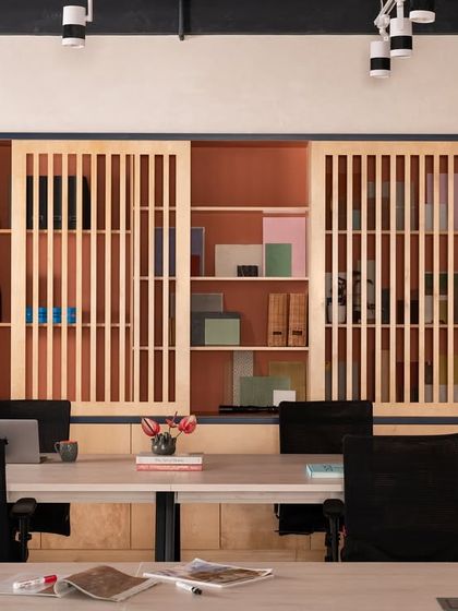 Behind the main workstations, I designed this storage unit with slatted sliding doors. It keeps materials and files organized and accessible, while the warm wood and terracotta-colored interior add texture and depth to the space.