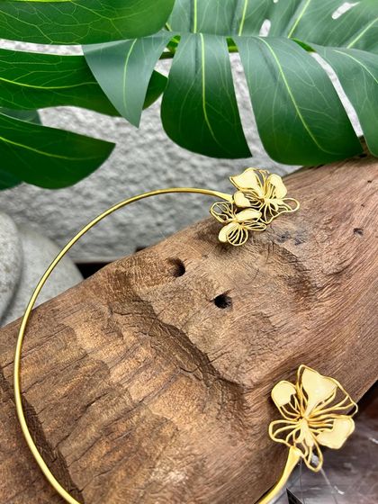 A modern and minimalist choker, featuring two delicate cut-out flowers on a simple gold band.