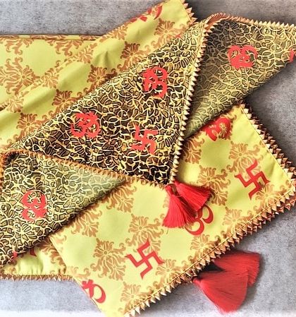 This traditional antarpat features auspicious symbols like 'Om' and the 'Swastik' printed on vibrant yellow and green fabric. The red tassels add a classic touch, perfect for a traditional wedding ceremony.